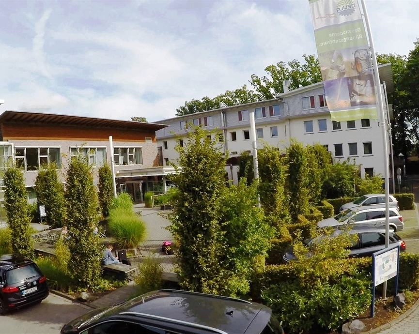 Gebäude der DEULA Westfalen-Lippe mit grünen Pflanzen und Parkplatz davor.